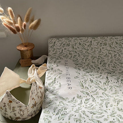 Floral-patterned fabric with 'Little Bear' branding on a surface, next to decorative items.