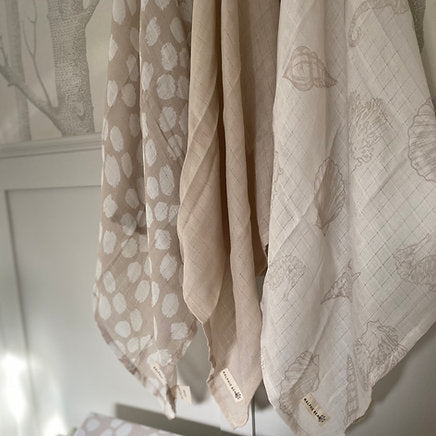 Three patterned cloths hanging on a rack with a neutral background