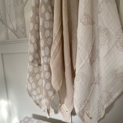 Three patterned cloths hanging on a rack with a neutral background