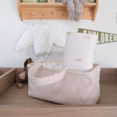 Nursery with wooden shelf, baby clothes, and toys on a white wall.