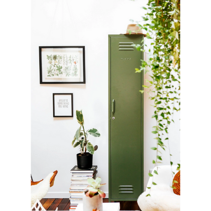 Green metal locker in a room with plants and framed pictures on the wall.