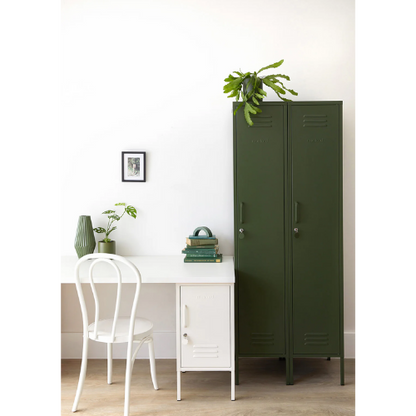 Green metal locker next to a white desk with a chair and plants in a room.