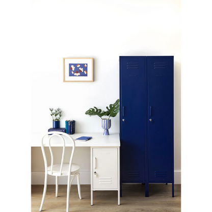 Blue locker next to a white desk with a chair, plants, and books on a light background