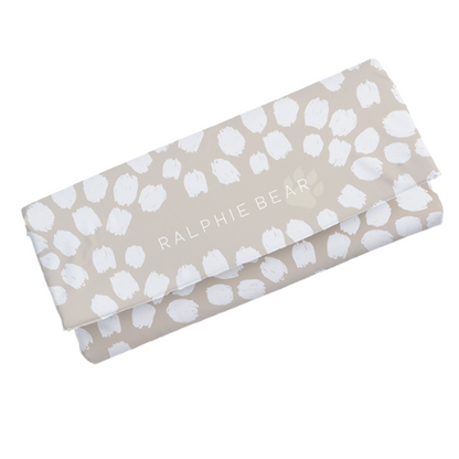 Folded fabric with white paw prints and 'Ralphie Bear' text on a beige background