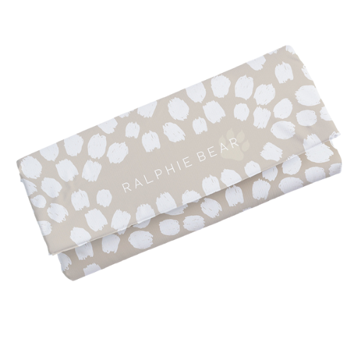 Folded fabric with white paw prints and 'Ralphie Bear' text on a beige background