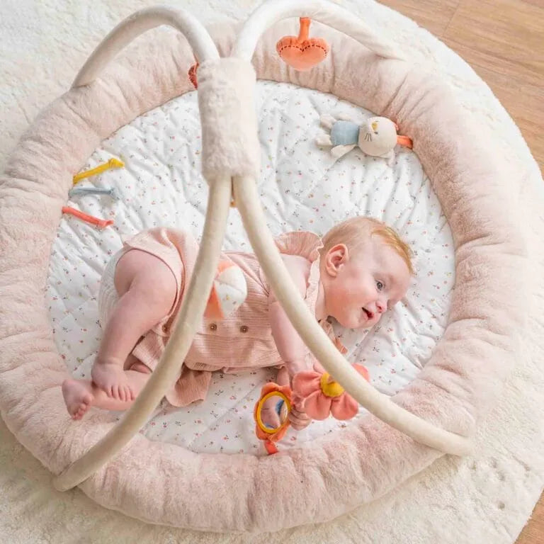 Baby lying in a pink baby bouncer with toys