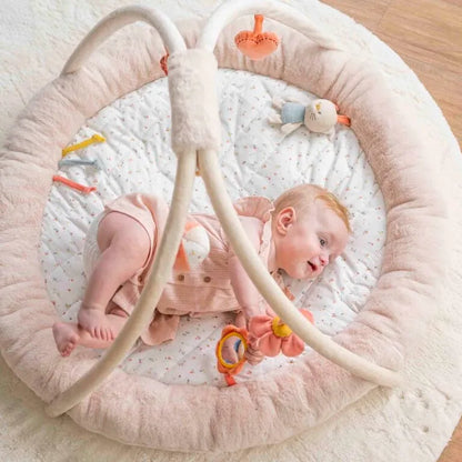 Baby lying in a pink baby bouncer with toys