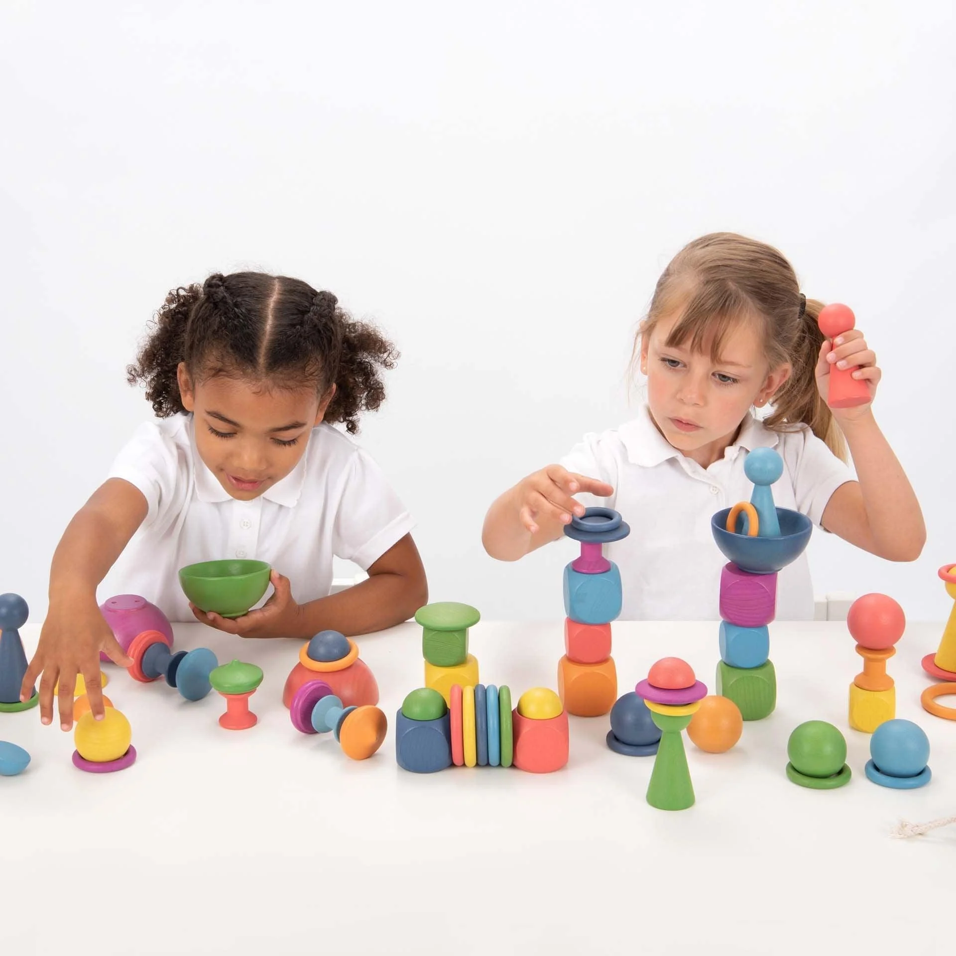Two children playing with wooden rainbow loose parts.