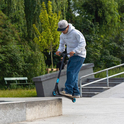 Person riding a scooter on a concrete path with greenery in the background