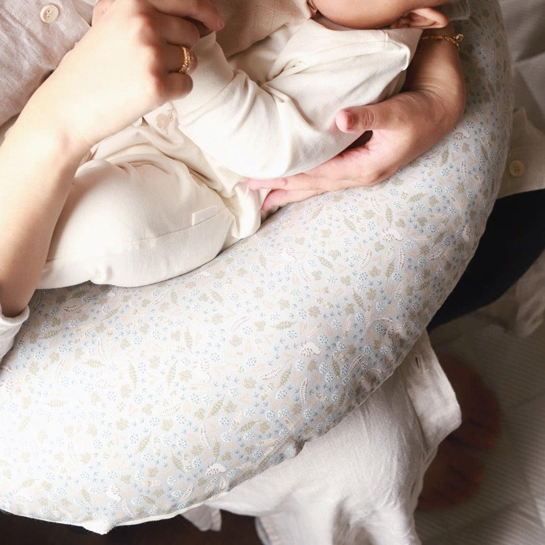 Person holding a baby in a floral-patterned cushion