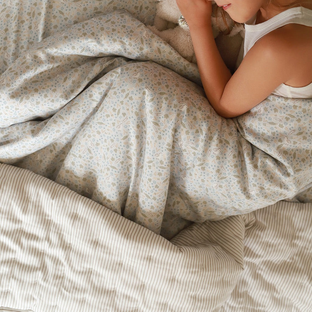 Person lying in bed under floral-patterned duvet