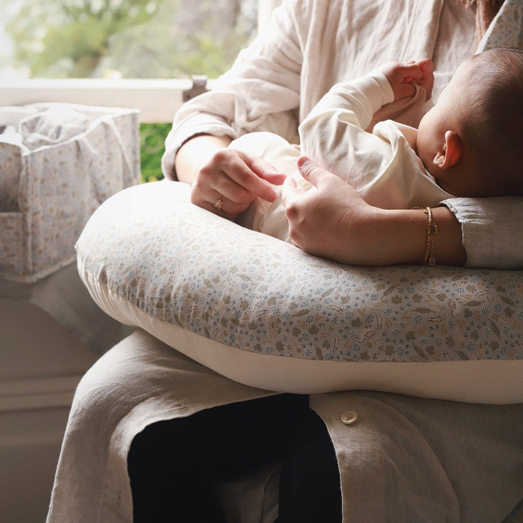 Person holding a baby on a cushioned surface with a blurred background