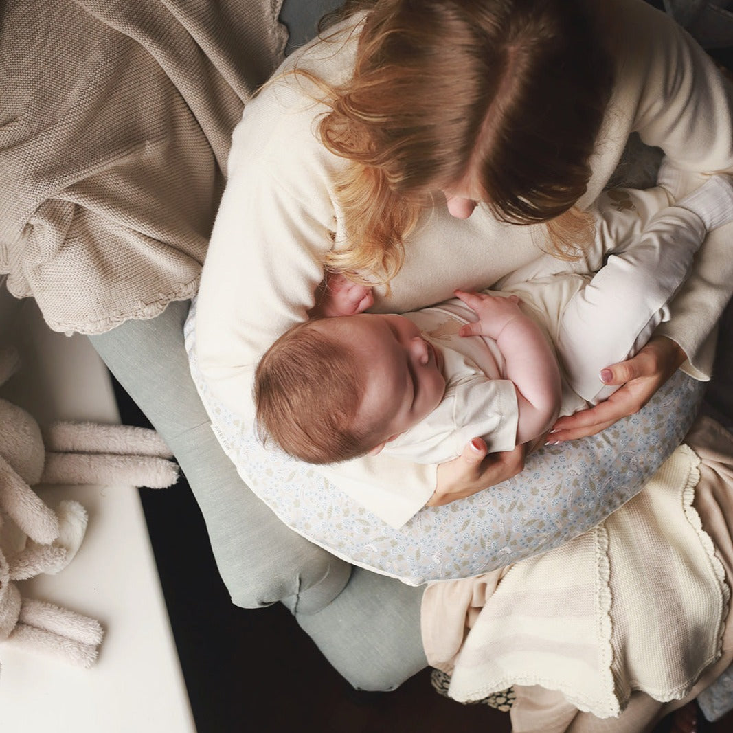 Woman holding a baby in a soft, cushioned cradle