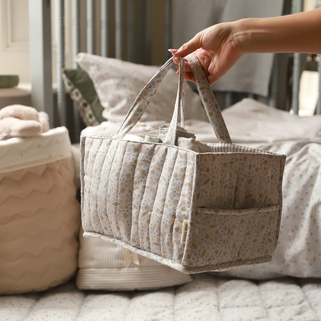 Person holding a quilted fabric basket with floral pattern in a home setting.