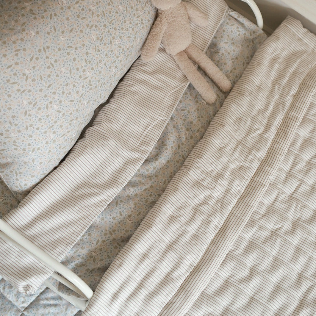 Close-up of beige textured fabric with a teddy bear toy on a neutral background