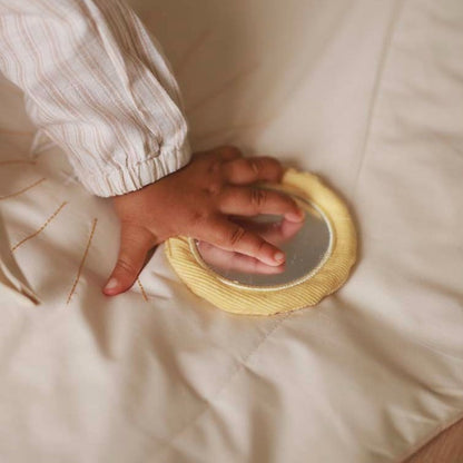 Hand touching a round, textured object on a soft beige surface