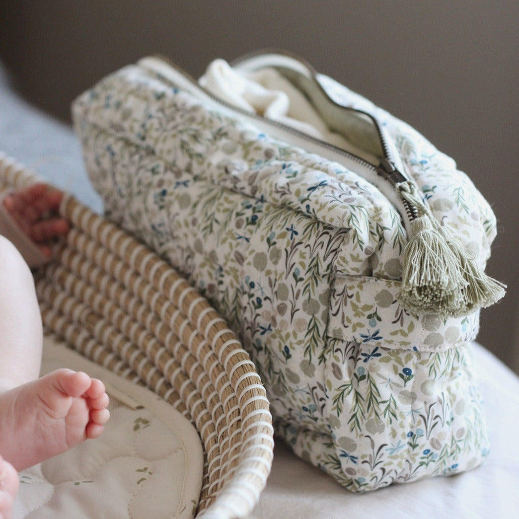 Floral-patterned makeup bag with tassel on a neutral background