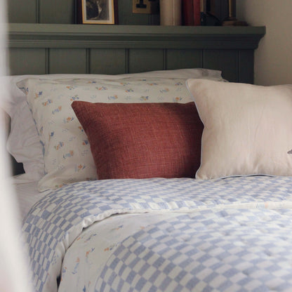 Bed with patterned bedding and pillows against a wooden headboard.
