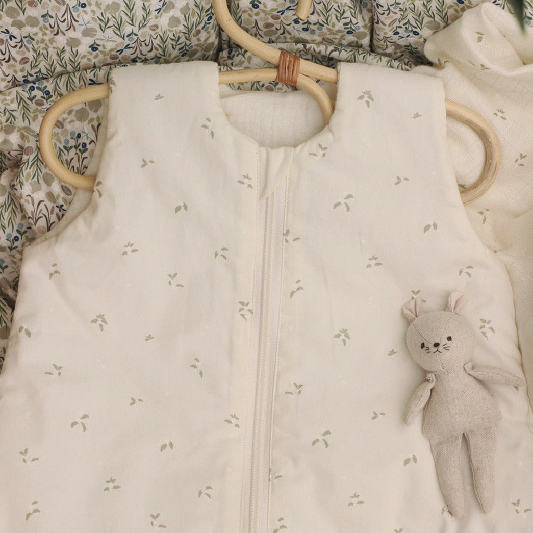 Baby sleeping bag with floral pattern and plush toy on a floral blanket