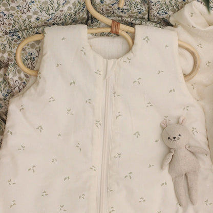 Baby sleeping bag with floral pattern and plush toy on a floral blanket