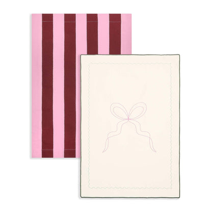Two towels, one with pink and purple stripes and the other with a bow design on a white background.