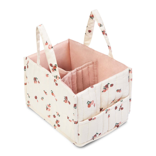Pink baby crib with floral patterned sides and handles on a white background