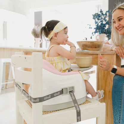 Child in a high chair with a woman sitting next to her at a dining table.