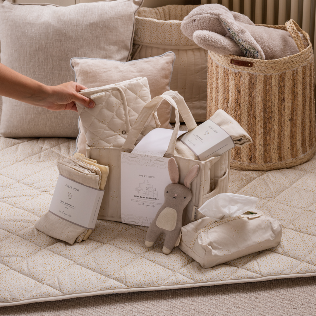 Baby care products including a quilt, toys, and diapers on a quilted surface.