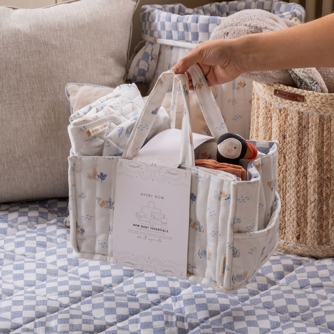Baby essentials bag with items on a checkered blanket