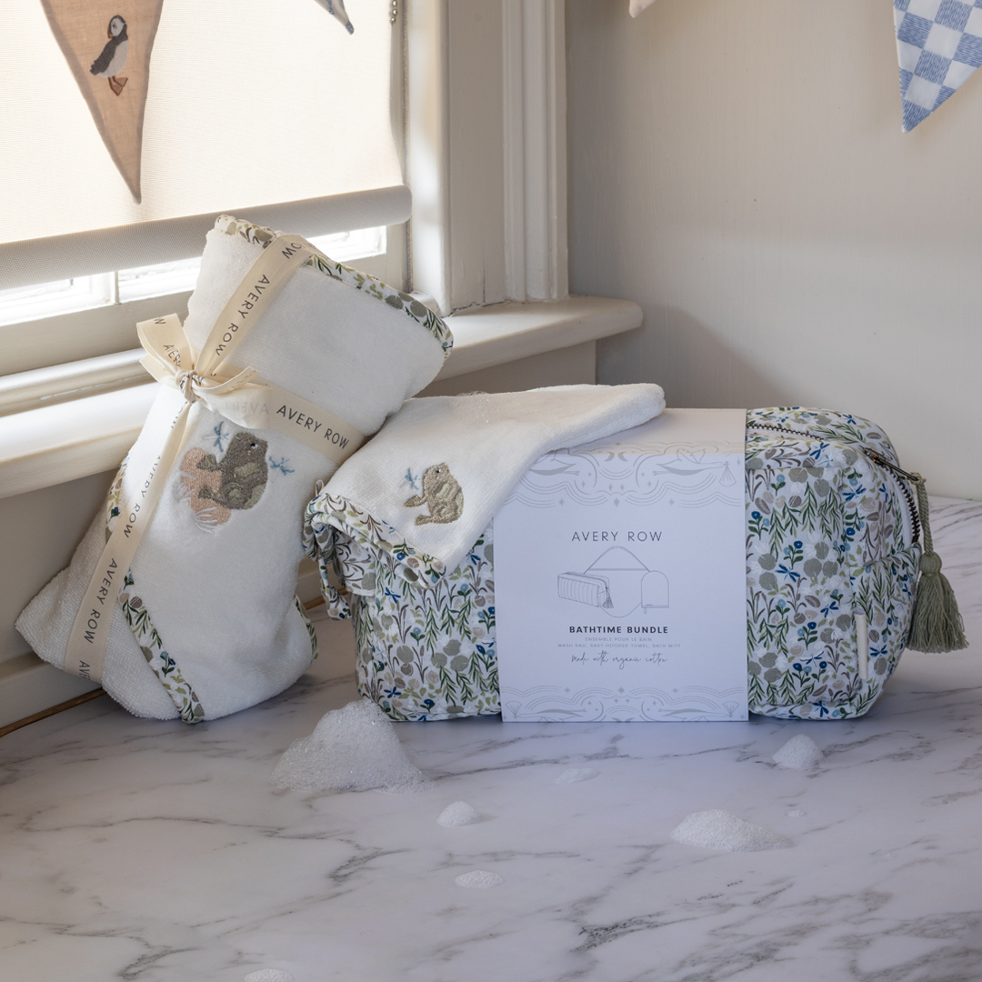 Baby gift set with crib sheet, pillow, and bag on a marble surface.