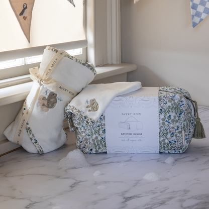 Baby gift set with crib sheet, pillow, and bag on a marble surface.