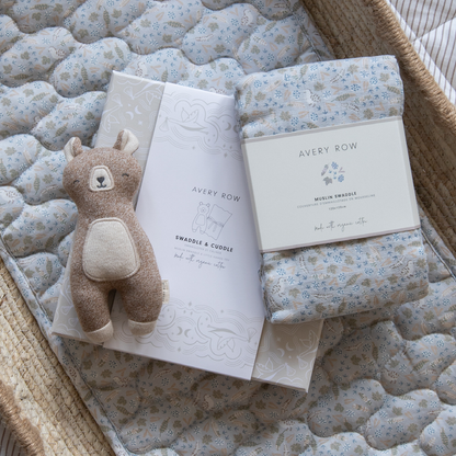 Baby swaddle, plush toy, and book on a textured surface with 'Avery Row' branding.