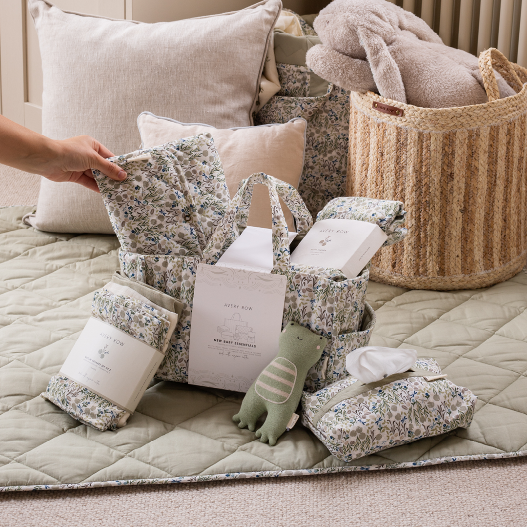 Baby items including blankets, pillows, and a toy on a quilted surface.
