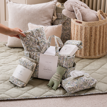 Baby items including blankets, pillows, and a toy on a quilted surface.