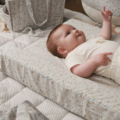 Baby lying on a floral-patterned mattress with a neutral background