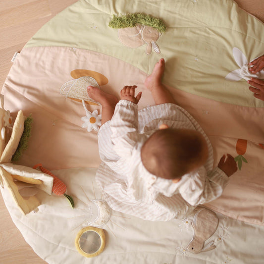 Baby playing on a soft play mat with toys