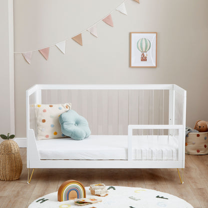 Kimi Cot Bed  in toddler style with a Acrylic spindles in a bedroom with rug and toys.