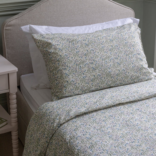Floral patterned bedding set on a bed with a side table in the background.