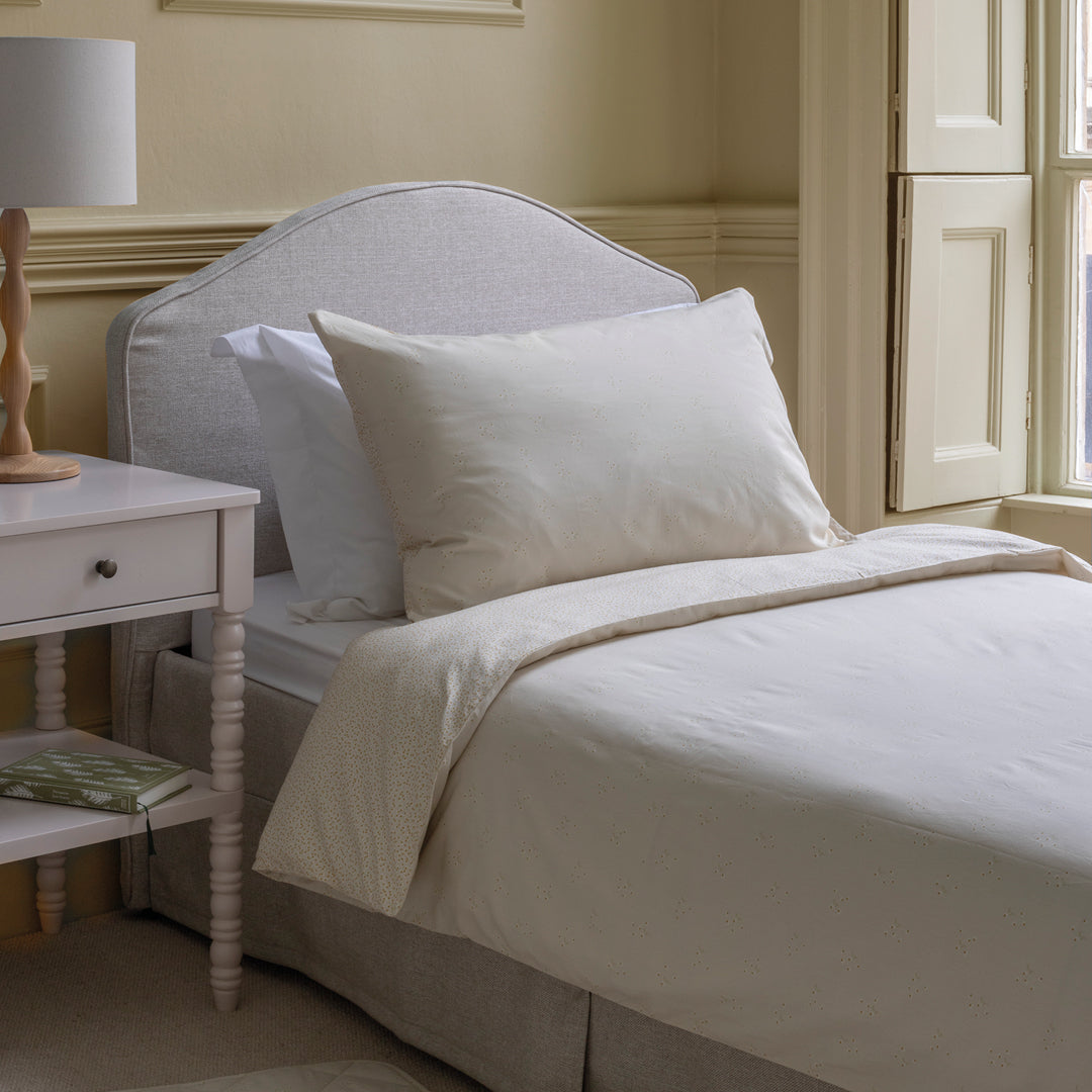 Neatly made bed with white bedding in a bedroom setting.