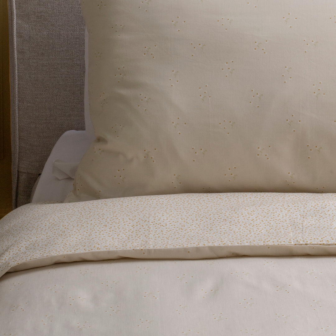 Close-up of beige textured bedding with a pillow in the background