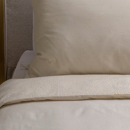 Close-up of beige textured bedding with a pillow in the background