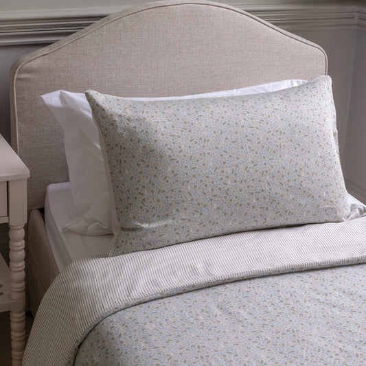 Floral-patterned pillow on a bed with a neutral headboard