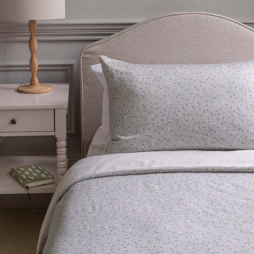 Bedroom with a bed featuring patterned bedding and pillows, next to a nightstand with a lamp.