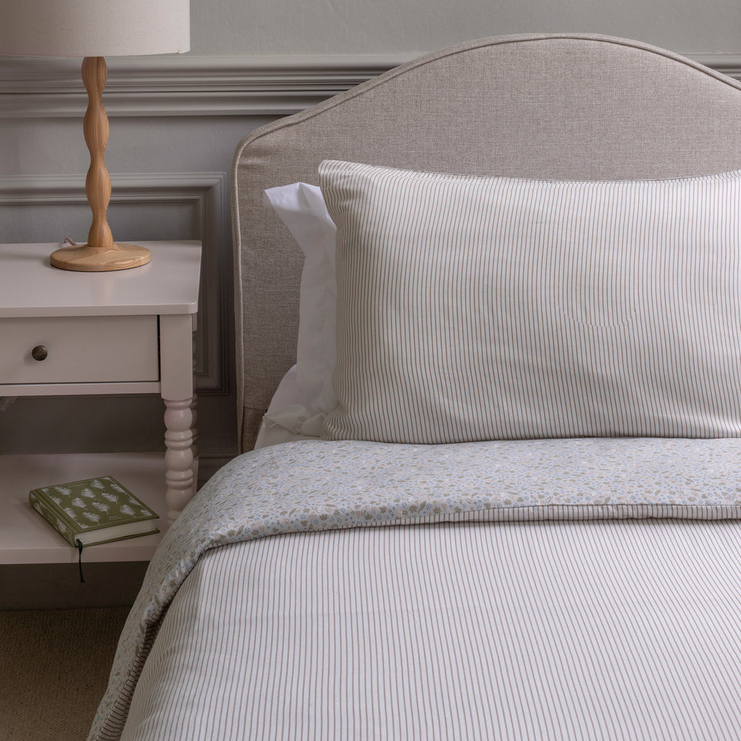 Neatly made bed with striped bedding and pillows in a bedroom setting.