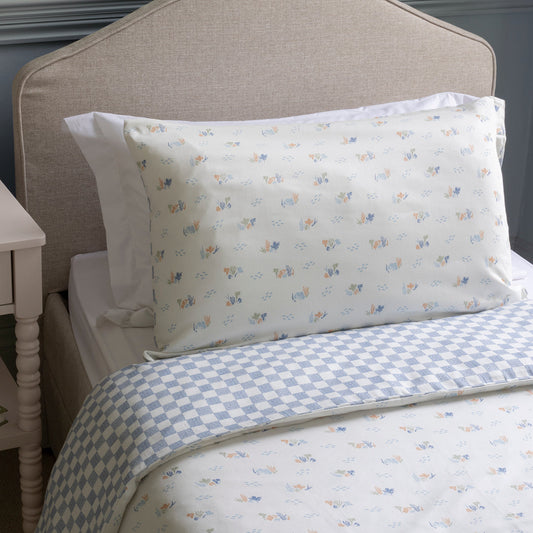 Bed with checkered bedding and patterned pillows against a neutral headboard.