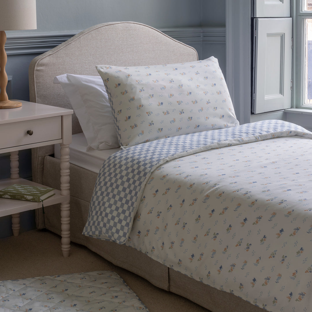Bedroom with a bed featuring patterned bedding and pillows, next to a nightstand.
