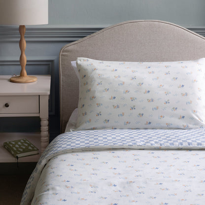 Bed with floral-patterned bedding and pillow, nightstand with lamp in a bedroom setting.