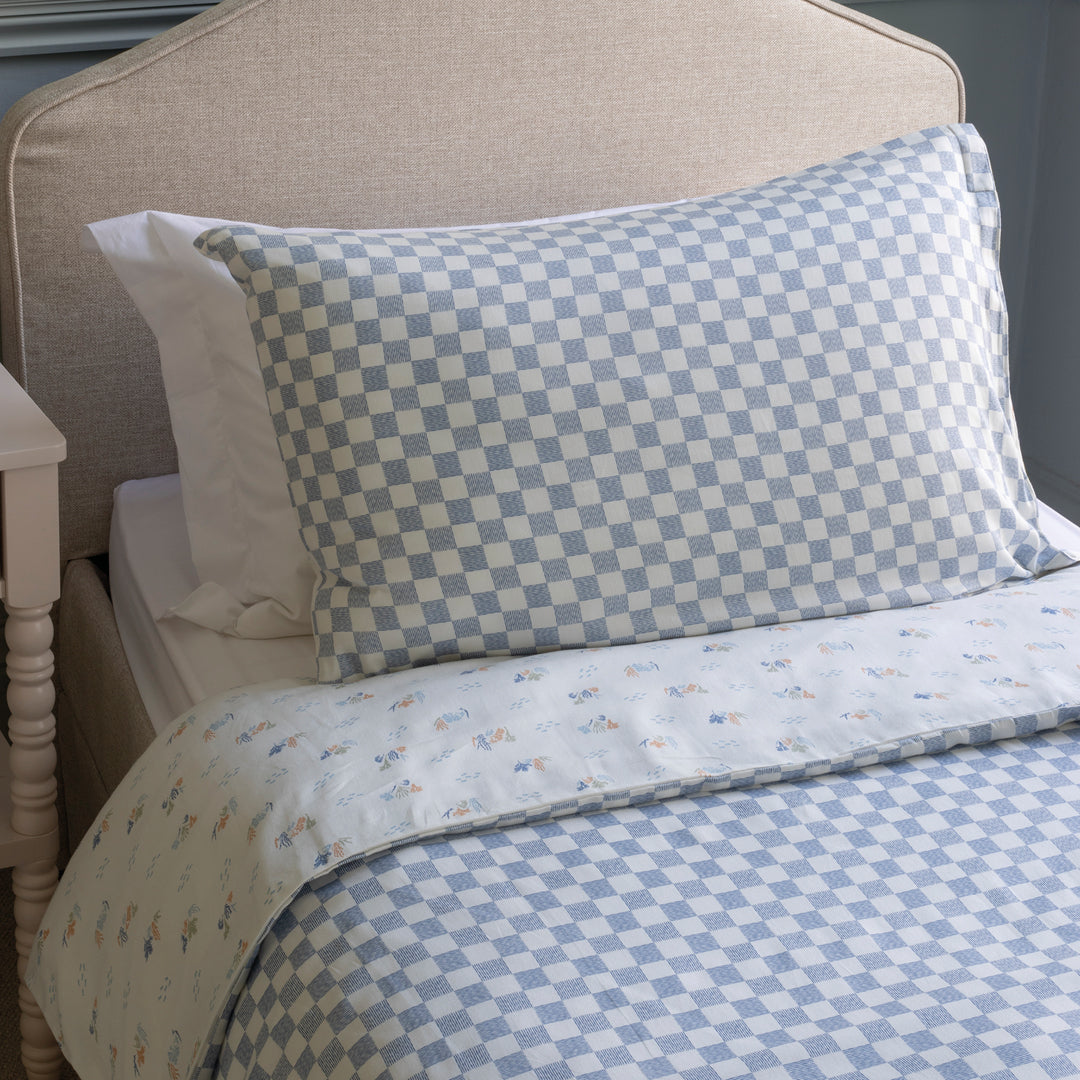 Bed with checkered blue and white pillow and bedding