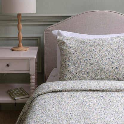 Floral bedding set on a bed with a nightstand and lamp in a bedroom setting.