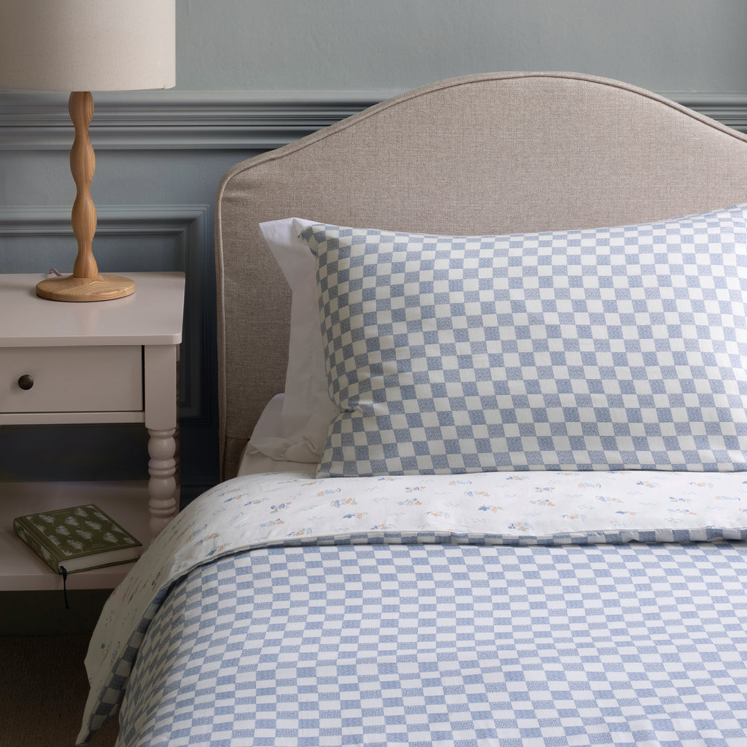 Bed with checkered bedding and pillows in a bedroom setting.
